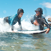 Surflehrer schiebt Kinder in die Wellen