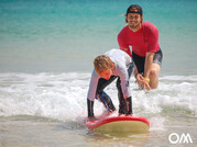 Surflehrer pusht Kind in die Welle