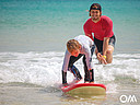 Kinder Surfkurs, Surflehrer schiebt Schüler in die Welle